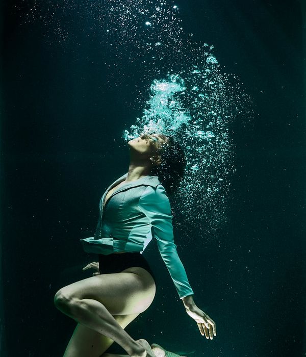 Person in a dynamic and fluid pose against a cream background.